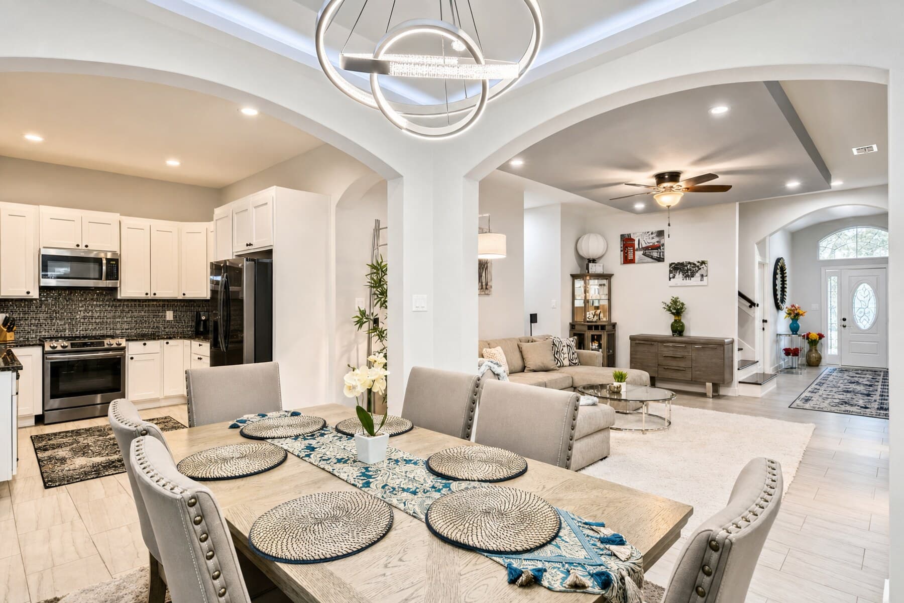 Open-concept living and dining area with a modern ring chandelier and styled table, prepared for a furnished stay.